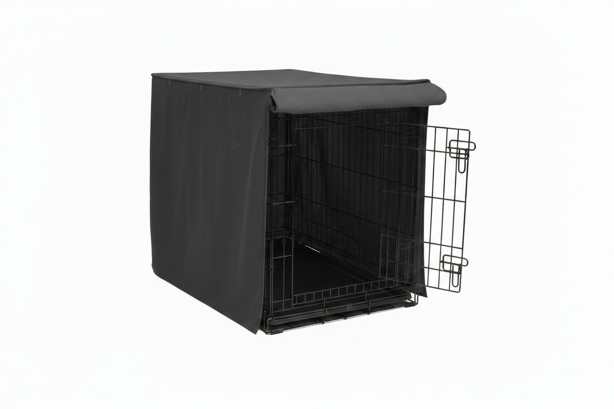 Dog sitting next to a black dog crate with a cover on a white background