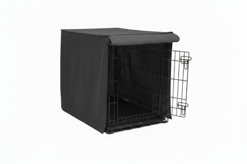 Dog sitting next to a black dog crate with a cover on a white background
